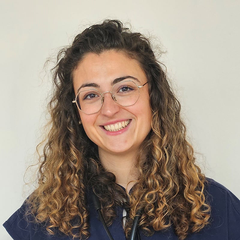 Une personne avec des lunettes souriante.