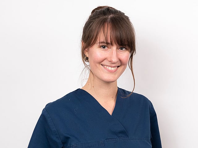 Une personne en blouse bleue souriante.