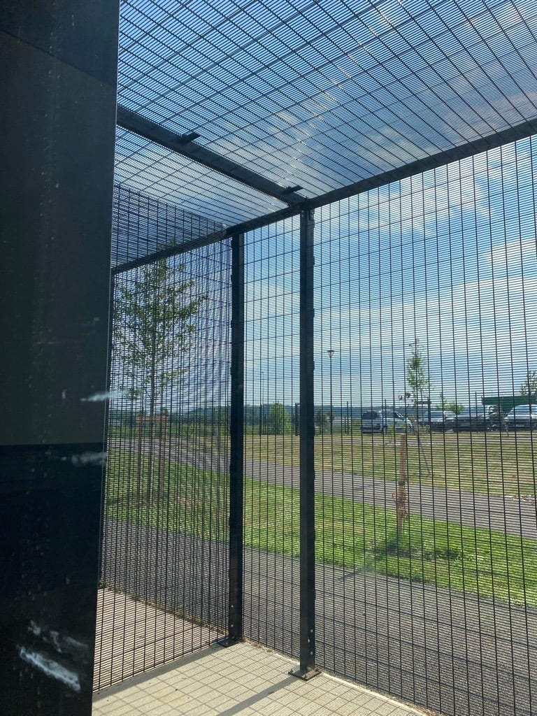 Une cage avec un arbre en arrière-plan.
